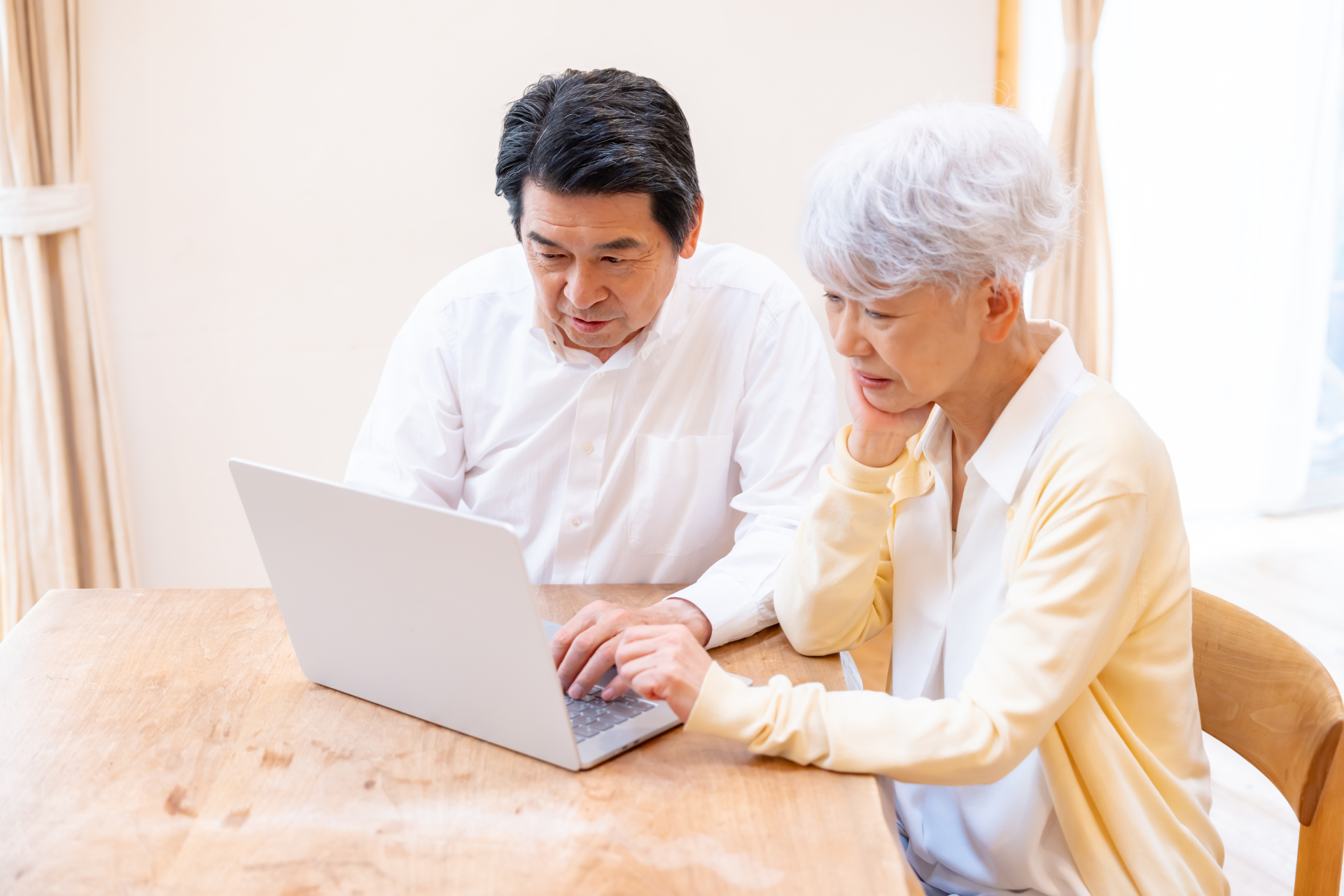 ノートパソコンを見ながら老後資金について考えるシニア夫婦